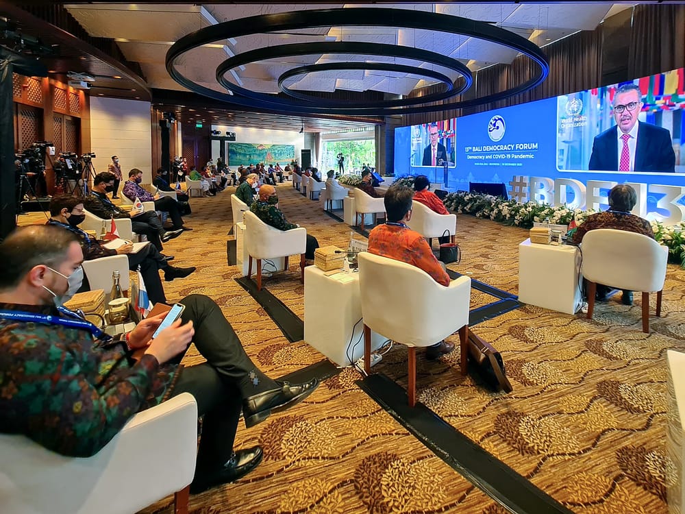 People sitting in front of a Wide Screen in an Event